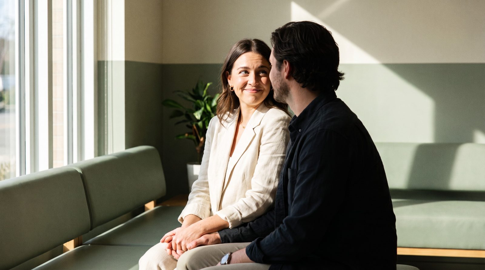 A couple sitting together in a bright waiting area before their first counseling session